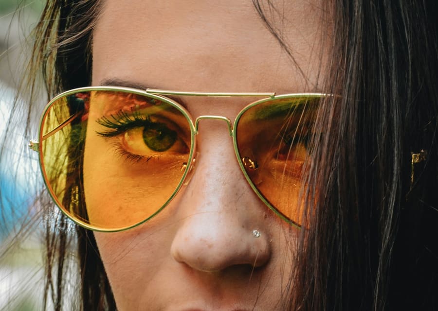 Rosto de mulher com óculos de sol aviador de lente amarela
